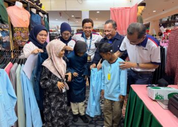 NAIB Presiden Kanan Bahagian Pelaburan & Pengurusan Harta UDA Holdings Bhd. Mohd. Nazri Jamiran (kanan) cuba memakaikan baju kepada salah seorang penerima pada Program CSR Sinar Ramadan Uda di Angsana Johor Bahru Mall di Johor Bahru hari ini. - UTUSAN/BAAZLAN IBRAHIM