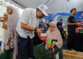SHARIMAN Yusuf Mohamed Zain mengagihkan bubur lambuk kepada pengunjung pada program Kongsi Rezeki Alam Flora di Bazar Ramadan Presint 3 Putrajaya. - UTUSAN/FAISOL MUSTAFA
