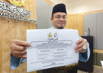 HILMI Abdullah menunjukkan contoh notis arahan penutupan premis pasar raya besar, pasar raya dan kompleks beli-belah pada 1 Syawal dan hari pertama Aidiladha di Kelantan selepas Mesyuarat Mingguan Exco di Kota Darulnaim, Kota Bharu, Kelantan hari ini-UTUSAN/YATIMIN ABDULLAH.
