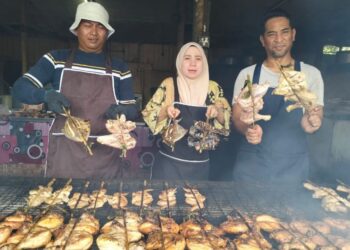 WAN Marini Wan Mohd. Nazi (tengah) bersama Saifulizam Yasok (kanan) dan pekerjanya menunjukkan ayam percik yang dibakar atas arang di Jalan Pasir Mas-Salor, Kota Bharu, Kelantan. - UTUSAN/ROHANA ISMAIL
