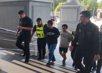 TERTUDUH (tengah) diiringi anggota polis semasa tiba di pekarangan Kompleks Mahkamah Kuala Lumpur, hari ini. -UTUSAN