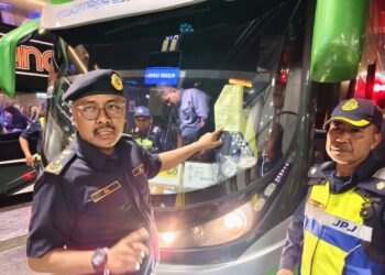 ZULKIFLY Ismail (kiri) menunjukkan kertas kuning yang dilekatkan pada bas yang telah diperiksa oleh JPJ dalam Ops HRA di terminal bas Penang Sentral, Butterworth, Pulau Pinang malam tadi.