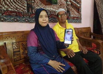 NOR Hayati Mat Hassan bersama Mohd. Sofian Abdul Rani menunjukkan gambar raya terakhir bersama anaknya pada tahun lalu ketika ditemui di Kampung Gong Bayor, Besut, Terengganu. - UTUSAN / WAN ZURATIKAH IFFAH WAN ZULKIFLI
