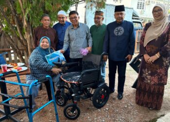 ROSLAN Hussin (tiga dari kanan) menyampaikan bantuan kerusi roda kepada orang kurang upaya (OKU), Fatimah Suriati Othman  sempena Program Ukhwah Madani PVATM di Dewan Dato' Mat Ghani di Kubang Kerian, Kelantan. - UTUSAN / ROSLIZA MOHAMED