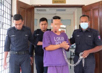 TERTUDUH (tengah) semasa dibawa oleh polis menghadiri prosiding perbicaraan di Mahkamah Sesyen, Gua Musang, Kelantan.