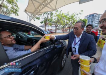 MOHD Zamri Ibrahim mengedarkan bubur lambuk kepada komuniti dan warga kampus UMT sempena program Kongsi Rezeki Ramadan anjuran UMT dan Nestle.