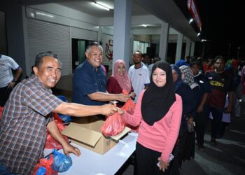 ROZABIL Abd Rahman (tengah) menyerahkan daging tempatan yang dijual pada harga serendah RM15 sekilogram bersempena program Jualan Rahmah UMNO Arau (Juara) di pekarangan pejabat UMNO Bahagian Arau, Perlis malam tadi.-UTUSAN/IZLIZAN OTHMAN