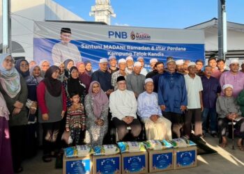 RICK Ramli (duduk, tengah) bergambar kenangan bersama penduduk setempat dalam Majlis Santuni Ramadan dan Iftar Perdana PNB di Kampung Telok Kandis, Alor Setar, semalam.