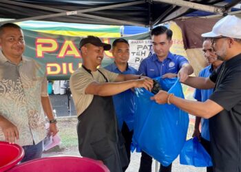 ABDUL Gafar Yahya (kanan) mengagih plastik sampah sempena Kempen Kebersihan Bazar dan Penyerahan Beg Sampah kepada peniaga di Bazar Ramadan Peremba, Alor Setar.