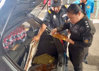 ANGGOTA penguat kuasa (kiri) menunjukkan minyak masak peket yang cuba diseludup oleh warganegara Thailand ke negara jiran semasa melalui pemeriksaan di ICQS Rantau Panjang, Kelantan.