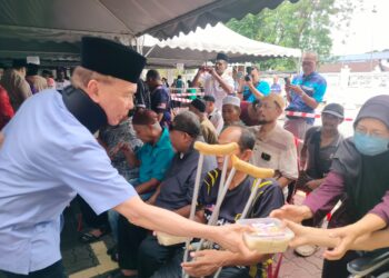 MOHD. Annuar Zaini mengagihkan bungkusan nasi beriani kepada orang ramai di pekarangan Masjid Sultan Idris Shah II atau Masjid Negeri, Ipoh hari ini.