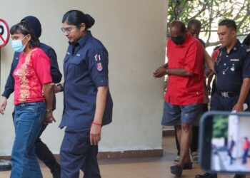 HALILA Abu Bakar (kiri) dan M. Jegathesan (dua dari kanan) diiringi anggota polis ketika dihadapkan ke Mahkamah Majistret George Town, Pulau Pinang atasu pertuduhan melakukan kelucahan melampau di tanah perkuburan Cina di Batu Gantung, Ayer Itam, pada 22 Mac lalu. - UTUSAN/DANIAL SAAD