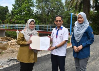 WAN Nur Ibtisam Wan Ismail (kiri) menyerah dokumen perakuan siap kerja kepada Wan Muhd, Rahimi Wan Salleh selepas majlis perasmian dan penyerahan Jambatan Wan Jamilah di Kampung Chatel Damai, Lata Rek, Kuala Krai, Kelantan. - UTUSAN/KAMARUL BISMI KAMARUZAMAN