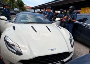 ISHAK Ismail (kiri) melihat kereta mewah yang dirampas menerusi Op Terma semasa sidang akhbar di Pejabat Penguatkuasaan JKDM Kota Bharu, Kelantan. - UTUSAN/ ROSLIZA MOHAMED