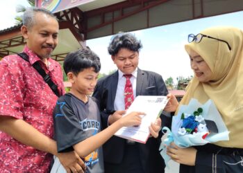 ADIB Adham Mohamad Izuddin (dua dari kanan) menunjukkan slip keputusan SPM kepada ibu bapanya di SMK Raja Permaisuri Bainun di Ipoh hari ini.