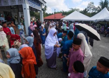 WAKIL keluarga mengagihkan duit raya kepada kanak-kanak selepas solat sunat Aidilfitri di Masjid Tertak Batu, Marang, Terengganu, baru-baru ini. – UTUSAN/PUQTRA HAIRRY