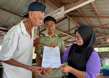 FAKHRUL Iman Zainudin (tengah) menunjukkan keputusan SPM cemerlang yang diperoleh kepada Zainudin dan ibunya Zarina Sood, 54, di Telok Kemang, Port Dickson hari ini.-UTUSAN/NOR SHAFIQAH MOHD GHAZALI