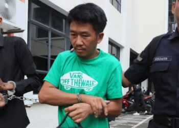 Seorang warga Myanmar, Sein Win Aung (berbaju hijau) didakwa membunuh rakan senegaranya awal bulan lepas, diiringi oleh anggota polis ketika tiba di Mahkamah Masjistret George Town, Pulau Pinang, hari ini.-UTUSAN/DANIAL SAAD