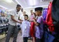 ZURAIDI Rahim membantu memilih uniform sekolah Muhamad Rizhan Rizqi (kanan) dan adiknya, Muhamad Raiqal Rayyan sambil ditemani Siti Nur Jamilah Jamaludin di Pekan Kuala Nerang, Padang Terap. -UTUSAN/ SHAHIR NOORDIN