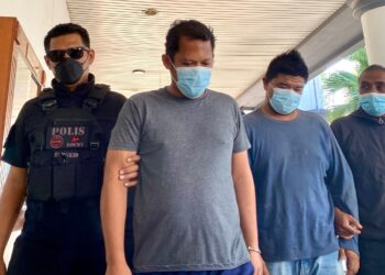 MUHAMMAD Izzudin Mustafa (dua kanan) dan Aliff Ezry Ismail dikawal anggota polis ketika dihadapkan ke Mahkamah Sesyen Alor Setar, Kedah atas kesalahan mengangkut migran, bulan lalu.
