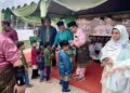 MAHFODZ Mohamed (tengah) memberi duit raya kepada kanak-kanak pada majlis Rumah Terbuka Aidilfitri Pas Negeri Johor di Bukit Pasir, Pagoh, Muar.