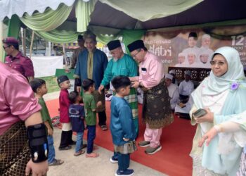 MAHFODZ Mohamed (tengah) memberi duit raya kepada kanak-kanak pada majlis Rumah Terbuka Aidilfitri Pas Negeri Johor di Bukit Pasir, Pagoh, Muar.