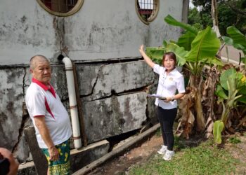 LEE Wern Yiing (kanan) bersama Daniel Koh menunjukkan kawasan tembok pagar kediaman yang telah runtuh sebahagian sejak bulan September tahun lalu.