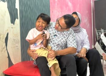 KHAIRUL Azwan Harun menyantuni Nurul Nadeera yang menghidap ketumbuhan pada pipi kanan di Kampung Gajah di Pasir Salak, Perak. – UTUSAN/AIN SAFRE BIDIN