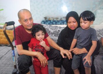 SITI Nur Azia Mohd. Rahim melihat tangan kiri Norull Habibul Annuar Ahmad akibat penyakit gout kronik di Taman Seri Mangga Pokok Mangga. – UTUSAN/AMRAN MULUP