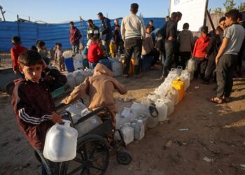 IBU dan kanak-kanak berdiri dekat kontena semasa menunggu untuk mendapatkan bekalan air di Gaza, 10 April lalu. - AFP