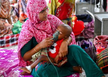 SEORANG ibu memegang alat nebulizer pada anaknya yang sedang menerima rawatan campak di wad pediatrik sebuah hospital di Dhaka, Bangladesh.-AFP