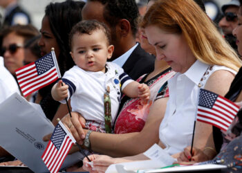 SEORANG bayi bermain dengan bendera AS pada upacara naturalisasi untuk warganegara baharu di Memorial Perang Dunia II di Washington, DC.- AGENSI