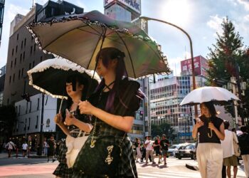 PEJALAN kaki memegang payung berjalan pada hari panas ketika gelombang haba melanda daerah Shinjuku, Tokyo.- AFP