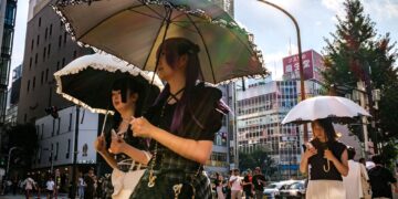 PEJALAN kaki memegang payung berjalan pada hari panas ketika gelombang haba melanda daerah Shinjuku, Tokyo.- AFP