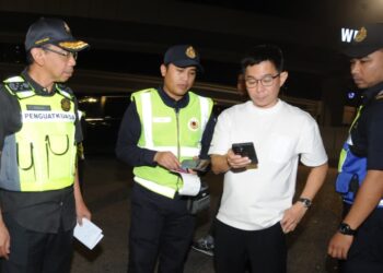 AZMAN Adam (kiri) melakukan pemeriksaan terhadap pemandu pada Operasi Bersepadu Bersama JPJ di susur keluar CIQ BSI, Johor Bahru disini. - UTUSAN/ RAJA JAAFAR ALI