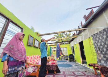 MOHD. Poad  Mohd. Yusop bersama isteri, Siti Ajar Abdullah menunjukkan  bumbung rumah yang diterbangkan ribut semalam ketika ditemui di Parit 7A Sungai Manik di Pasir Sala, Perak kelmarin. 
–  UTUSAN/AIN SAFRE BIDIN