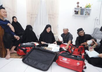 Mohd. Alham (kiri) melihat anak dan menantunya membuat persiapan  bagi menunaikan ibadah fardu haji di rumahnya di Kampung Sentosa, Masai, Johor Bahru. – UTUSAN/RAJA JAAFAR ALI