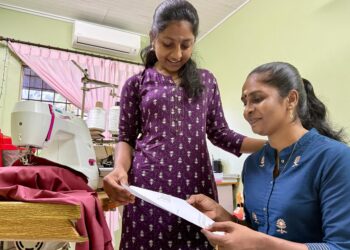 M. LEELASRI menunjukkan keputusan SPM yang diperoleh kepada ibunya, Kanniamah di rumah mereka di Johol, Kuala Pilah.-UTUSAN/NOR SHAFIQAH MOHD. GHAZALI