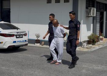 ZAINIZAN Zainal diiringi anggota polis dibawa keluar dari Mahkamah Majistret Rembau selepas prosiding sebutan semula kes pembunuhan Suri Narudin hari ini. -UTUSAN/NOR SHAFIQAH MOHD GHAZALI