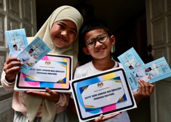 AESHA Khadeejah Anuar (kiri) dan Uwaid Al-Qarni menerima bantuan persekolahan dan sumbangan wang tunai daripada Perdana Menteri  di rumah mereka di Kampung Paya, Kuala Terengganu, Terengganu. -UTUSAN/PUQTRA HAIRRY