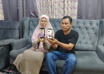 JAMALUDDIN Wahudin (kanan) Siti Roslina Misban menunjukkan gambar anak bongsu mereka yang lemas di Pantai Balok, Kuantan, Pahang.