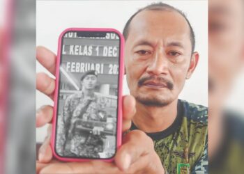 ROSAFINDI Tambi Chik menunjukkan gambar anaknya, Allahyarham Muhammad Amirul Raziq yang menjadi mangsa kekerasan di sebuah kem tentera di Bentong, Pahang.