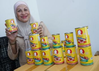 SALMAH Abu Bakar menunjukkan produk sardin keluarannya yang mula menembusi pasar raya besar baru-baru ini.