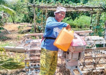 ABDULLAH Mat Yusof mengisi diesel ke dalam jentera pembajak dua roda di Kampung Teluk Jering Tumpat, Kelantan. - UTUSAN/ROHANA ISMAIL