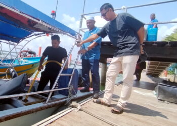 MOHD. Khaizol Che Mohd. Noor (kanan) melihat pengusaha bot mengisi bahan api untuk ke Pulau Perhentian dari Jeti Kuala Besut, Besut, Terengganu. – UTUSAN/WAN ZURATIKAH IFFAH WAN ZULKIFLI.