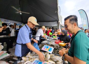 MUHAMMAD Faiz Fadzil (kiri) melayani pengunjung pada Program Jualan Ikan Murah sempena Program Madani Rakyat (PMR) 2026 Perak di Khemah Jualan Agro Madani di Bulatan Sultan Azlan Shah, Meru Raya di Ipoh hari ini.