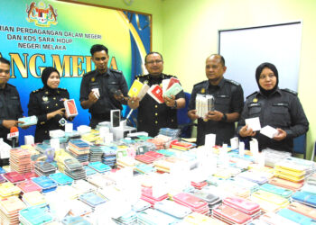 Mohd Hazimin Jamaluddin (tiga, kanan) menunjukkan sebahagian aksesori tiruan telefon bimbit yang dirampas dalam sidang akhbar di Stor Eksibit KPDN, Krubong, hari ini. - UTUSAN/AMRAN MULUP