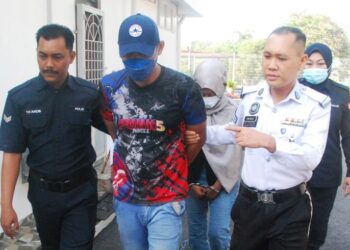 POLIS mengiringi Arif Fahmi Abd. Salam dan Nur Adila Najwa Ilham Ameerrullah di Mahkamah Majistret Jasin semalam. - UTUSAN/AMRAN MULUP