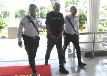 Mohd. Tamrin Ibrahim diiringi polis dibawa ke Mahkamah Majistret Alor Gajah hari ini. UTUSAN/AMRAN MULUP