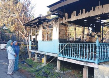 NORHASLINA Awang (kiri) melihat keadaan rumah pusaka yang didudukinya musnah dalam kebakaran di Kampung Buluh Gading, Kuala Terengganu. - UTUSAN/ERMA YUSNIDA JUSOH